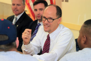 U.S. Secretary of Labor Thomas Perez, center, speaks with apprentices Mark McKunes, left front, and Tyrell Ellis, right front, apprentices in the Sheet Metal Workers Local No. 17 training program.