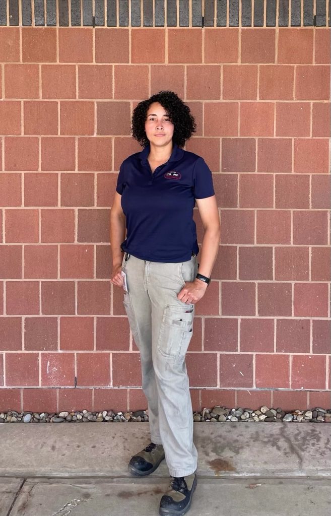 Adriana Farren posing for a picture in front of a wall.
