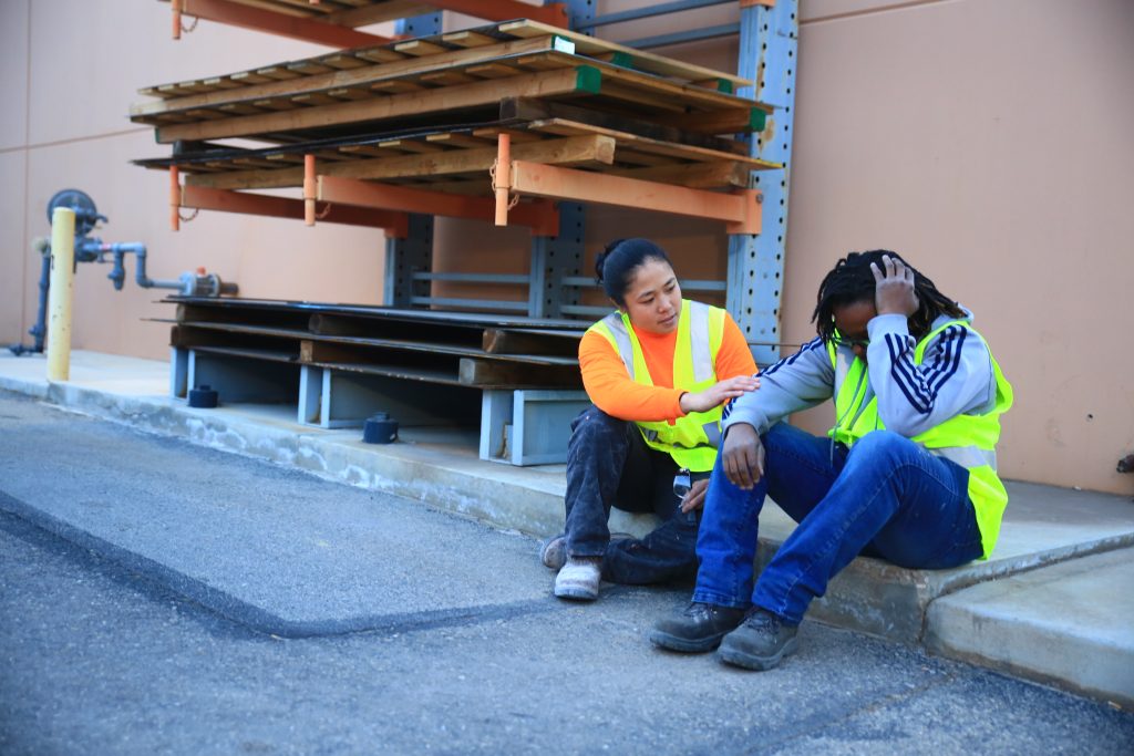 A woman consoling a man, both wearing yellow vests